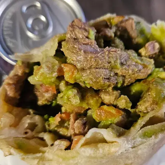 Carne asada taco topped with guacamole and salsa